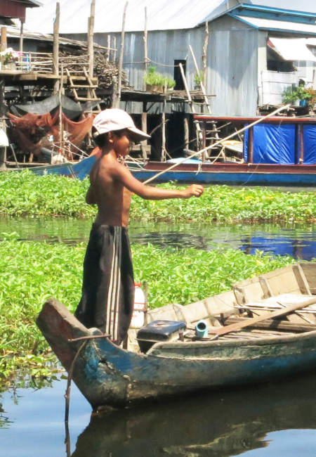 Enfant cambodgien pêchant depuis un bateau.